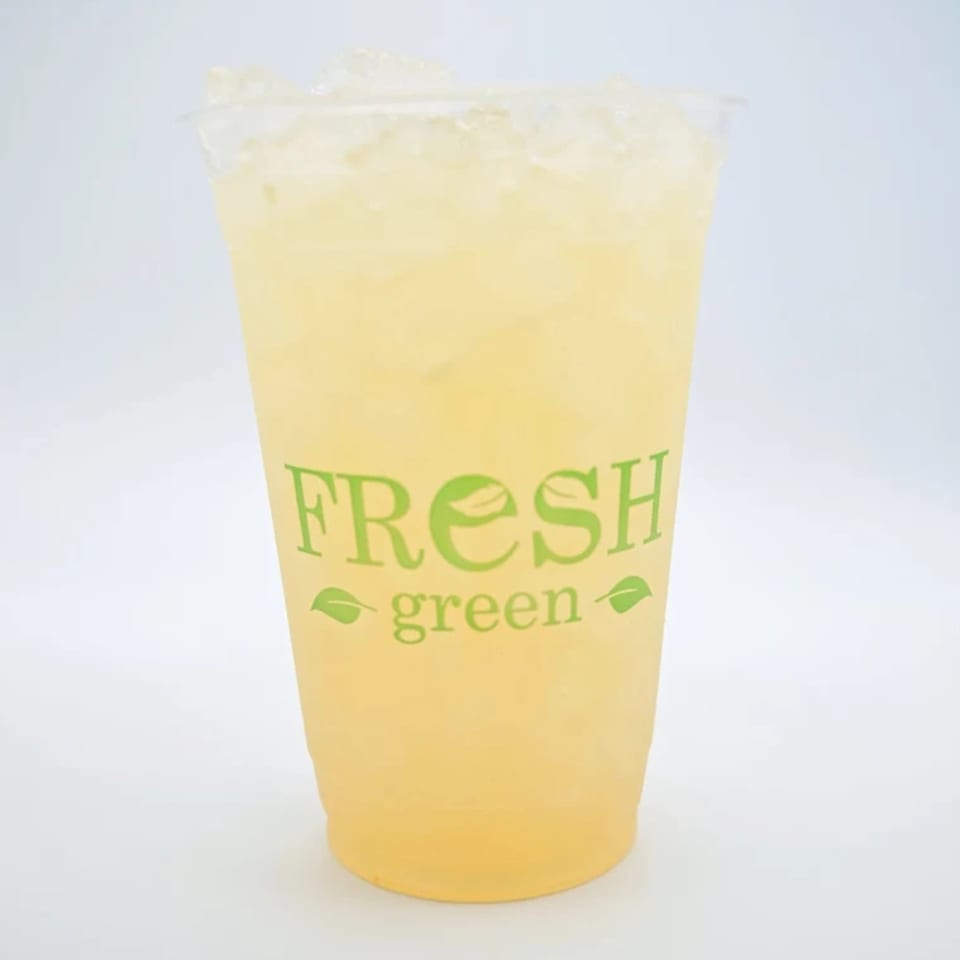 Iced lemonade in a clear plastic cup with the Fresh Green logo on a white background.